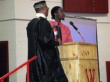 a man standing at a podium with a man standing behind him