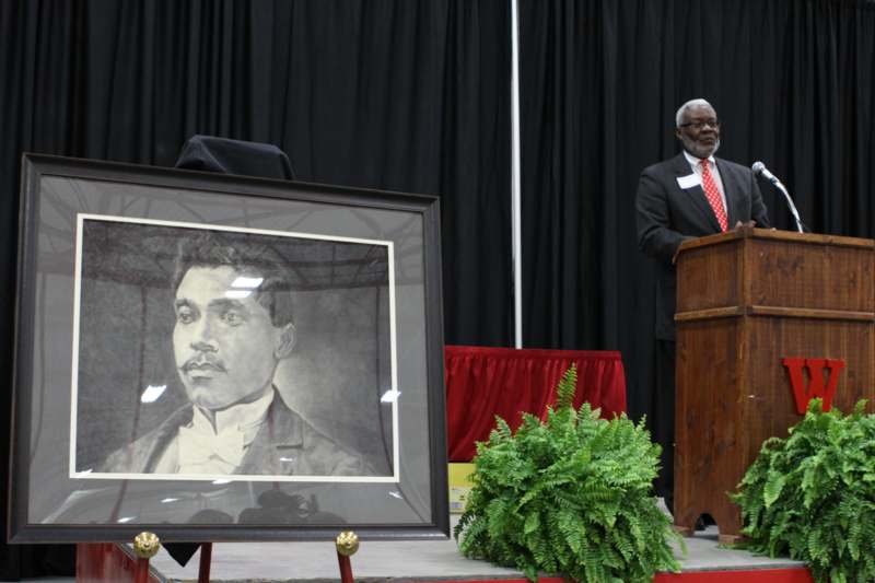 a man standing at a podium with a picture of a man