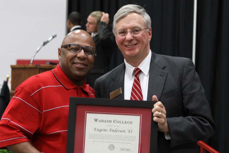 a man holding a framed plaque with a man in a red shirt