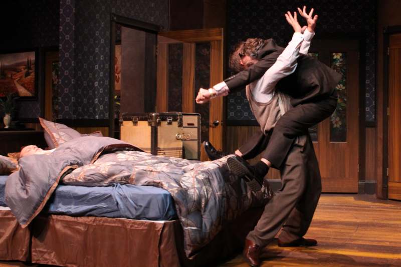 a man holding another man's leg while another man is jumping over a bed