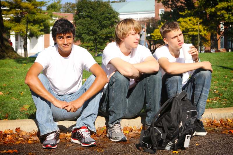 a group of young men sitting on a curb