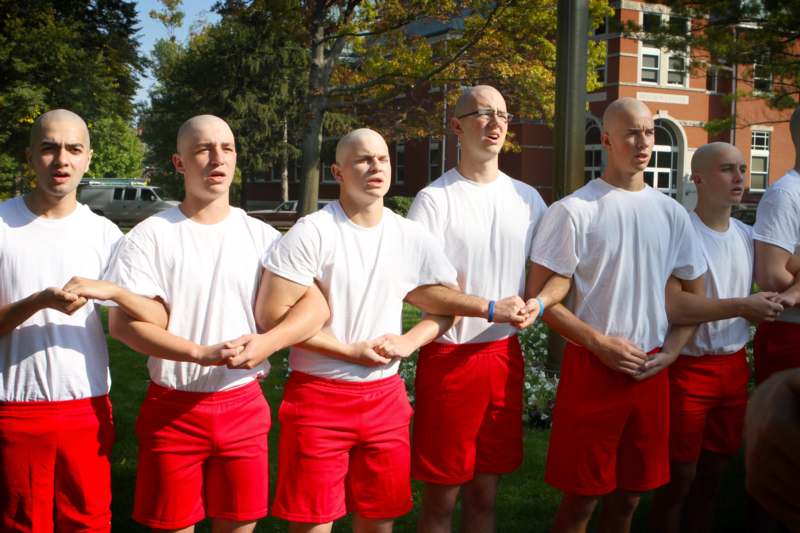 a group of bald men in red shorts