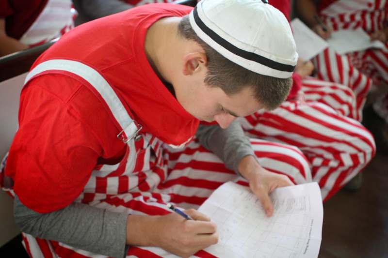 a man in red and white striped outfit writing on a piece of paper