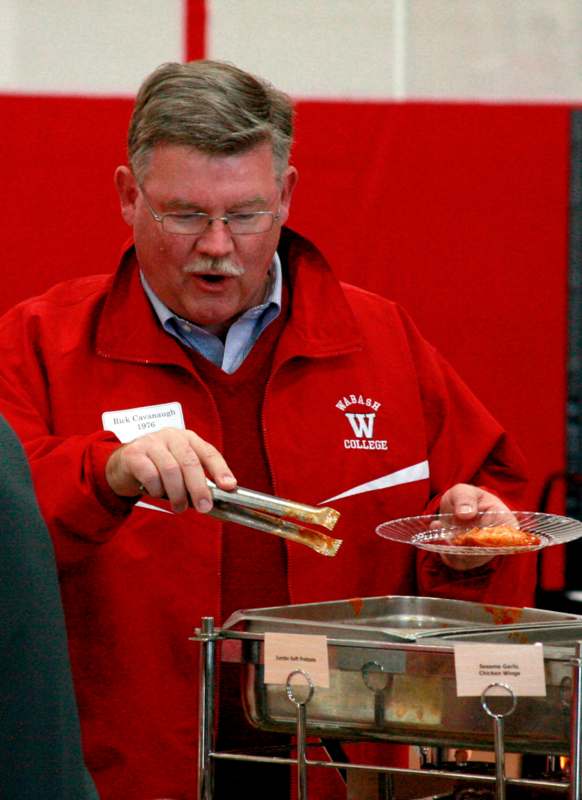 a man in red jacket holding tongs over a plate