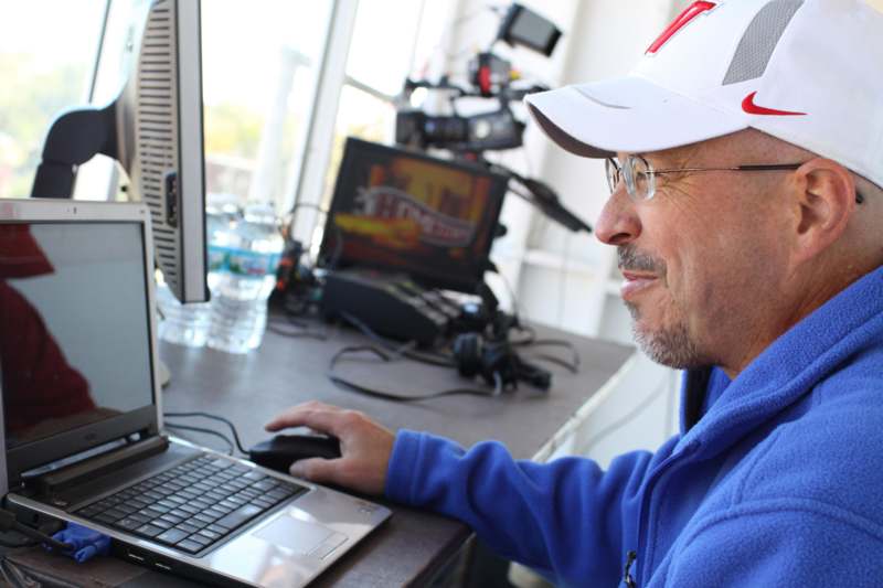 a man in a blue sweatshirt and white cap using a computer