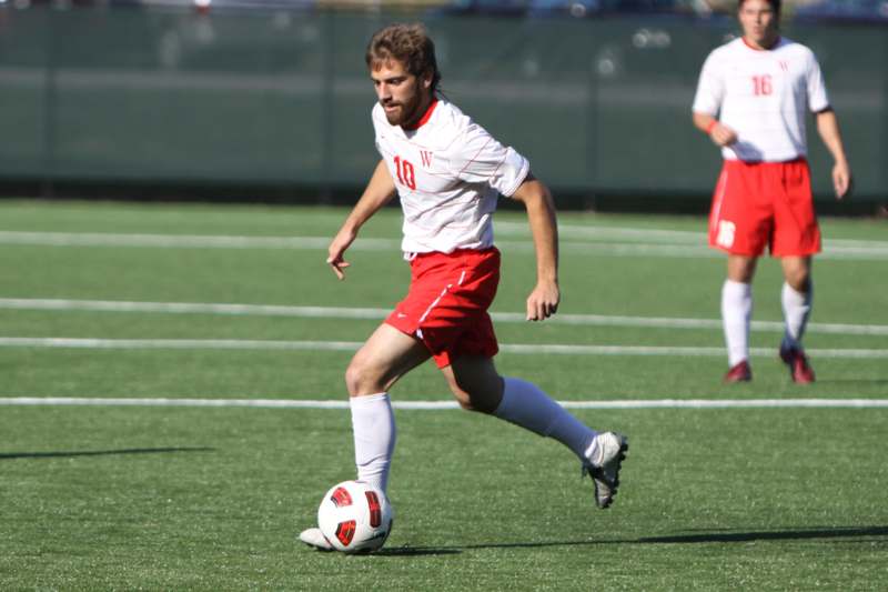 a man in a white shirt and red shorts kicking a football ball
