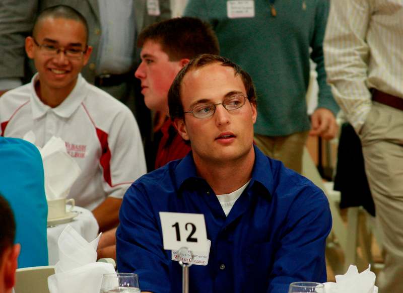 a man sitting at a table with a number on it