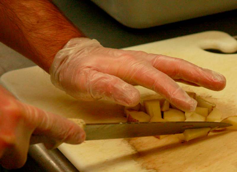 a person cutting food with gloves