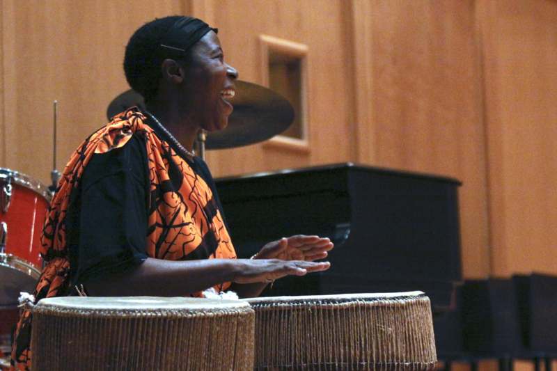 a woman playing drums in front of a piano