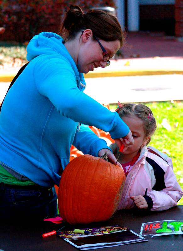 a woman and a girl carving a pumpkin