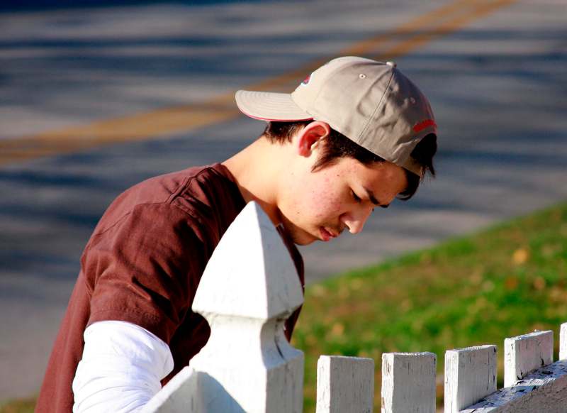 a man leaning on a white fence