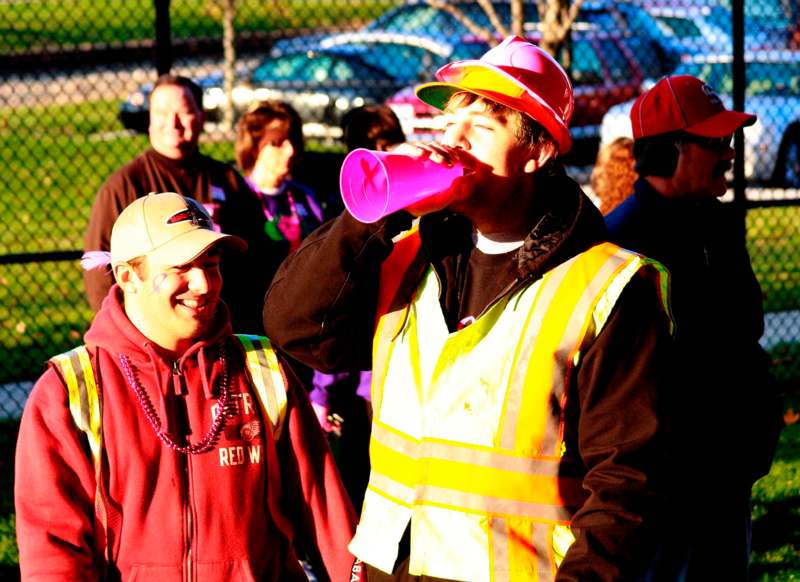 a man in a yellow vest drinking from a pink megaphone