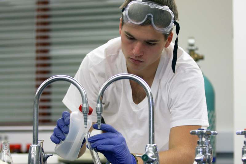 a man wearing goggles and gloves working in a lab