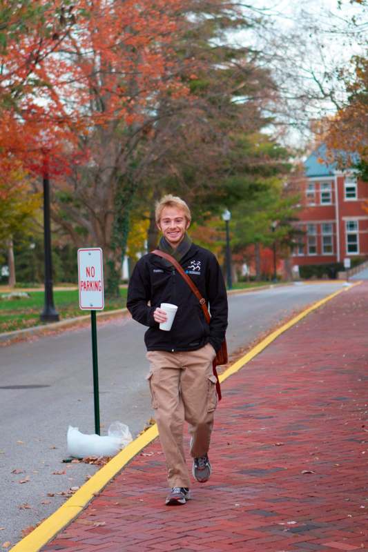 a man walking on a sidewalk holding a cup