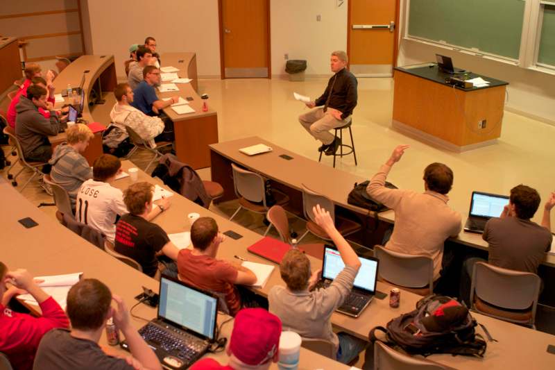 a man in a chair in front of a group of people in a classroom