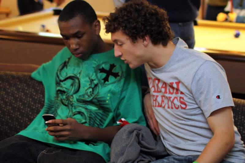 a group of young men sitting on a couch looking at a cell phone