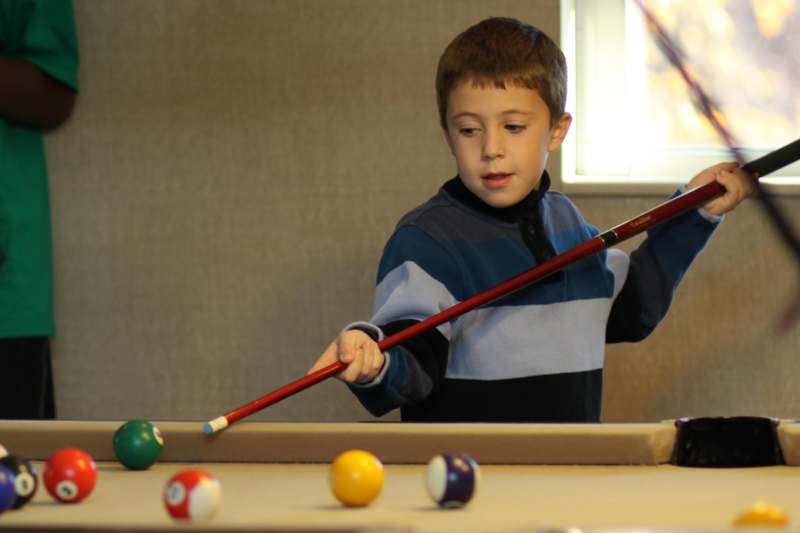 a boy holding a stick and playing pool