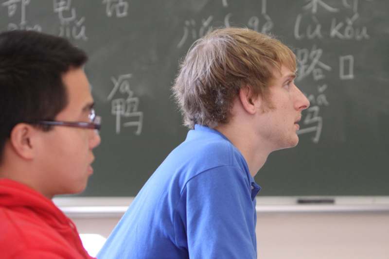 a man in a blue shirt sitting in front of a chalkboard
