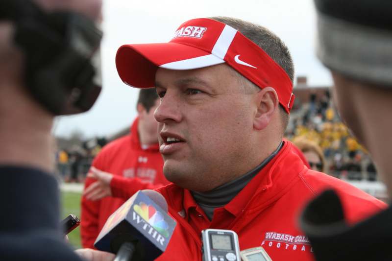 a man wearing a red visor and a red cap talking to a man with microphones