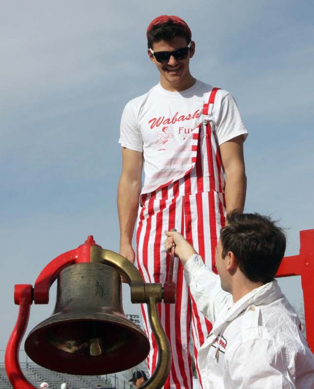 a man in a red and white striped apron standing on a bell