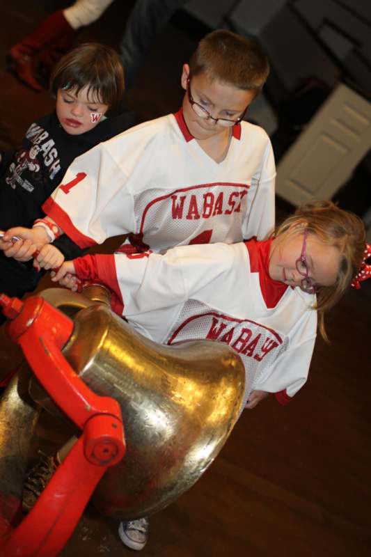 a group of kids playing with a bell