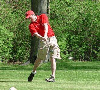 a man in a red shirt hitting a golf ball