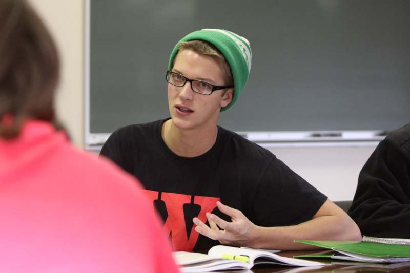 a man wearing a green beanie and glasses sitting at a table