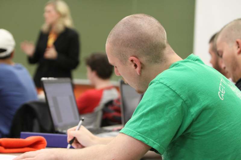 a man in a green shirt writing on a pen