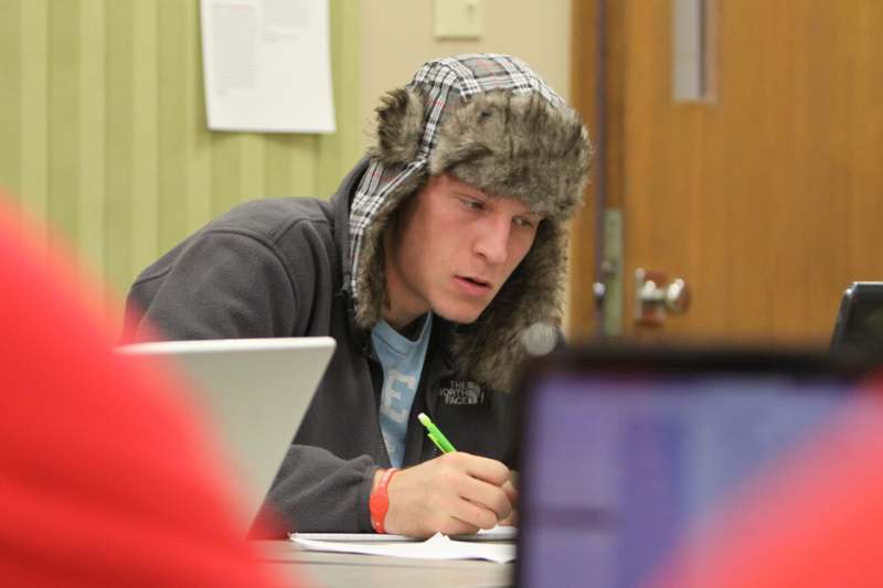 a man wearing a furry hat and sitting at a desk