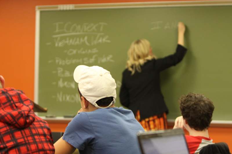 a group of people in a classroom writing on a chalkboard
