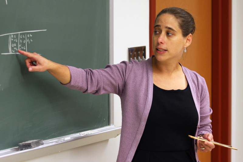 a woman pointing at a chalkboard