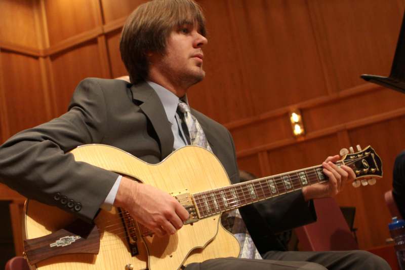 a man in a suit playing a guitar