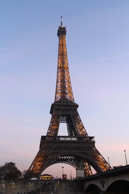a tall metal tower with lights with Eiffel Tower in the background