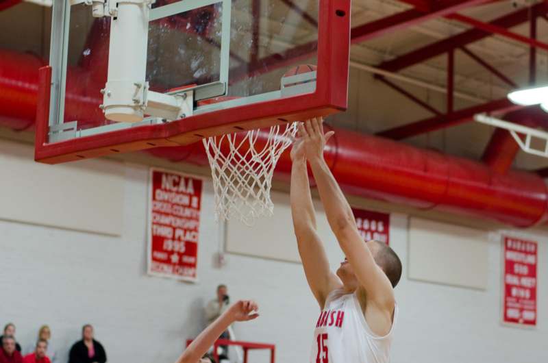 a man in a basketball uniform reaching for a basketball hoop