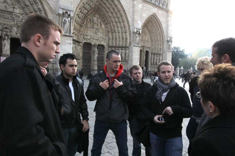 a group of men standing in front of a stone building