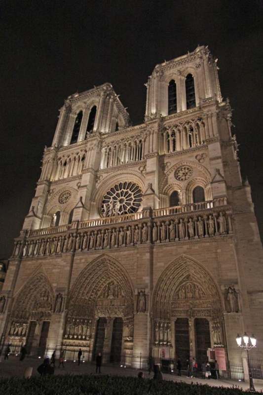 a large stone building with a rose window with Notre Dame de Paris in the background