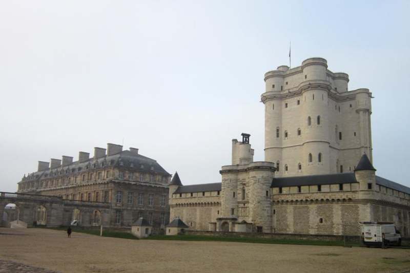 a large white castle with a large building with Château de Vincennes in the background