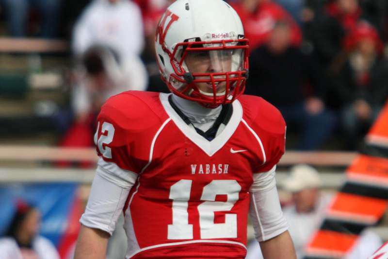 a football player wearing a red and white uniform with Ohio State University in the background