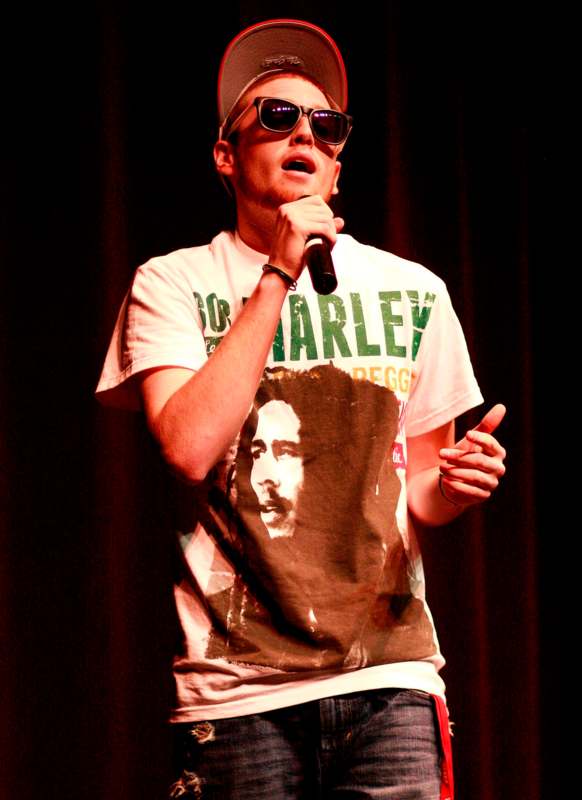 a man wearing sunglasses and a white hat holding a microphone