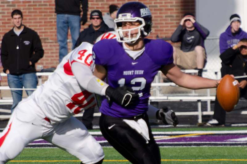 a football player in a purple uniform running with another player in the back