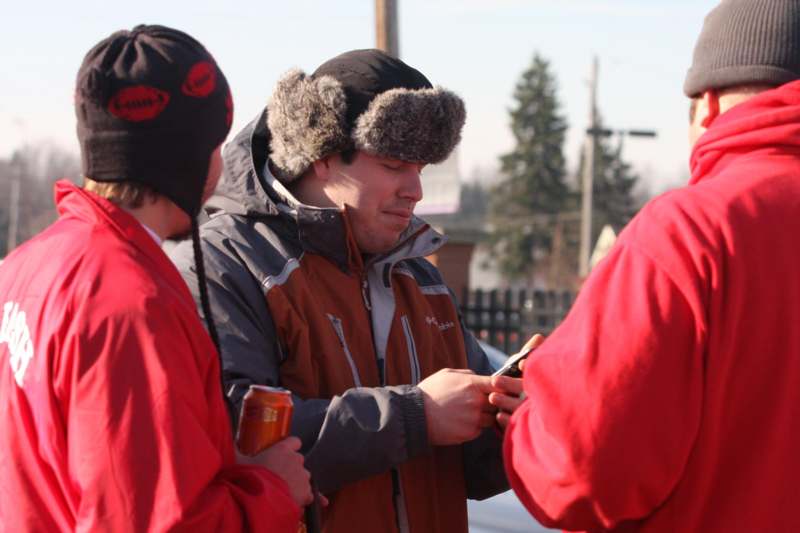 a group of men in winter clothes looking at a phone