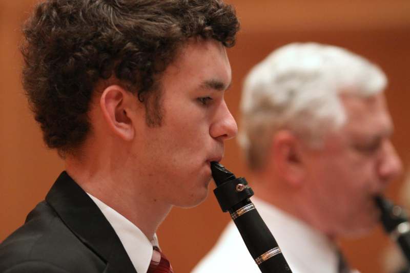 a man in a suit and tie playing a clarinet