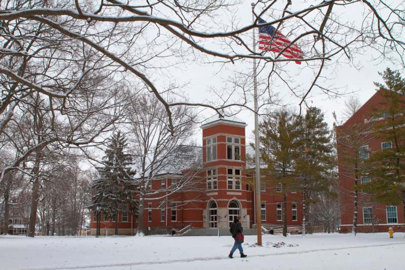 a person walking in the snow with Wabash College in the background