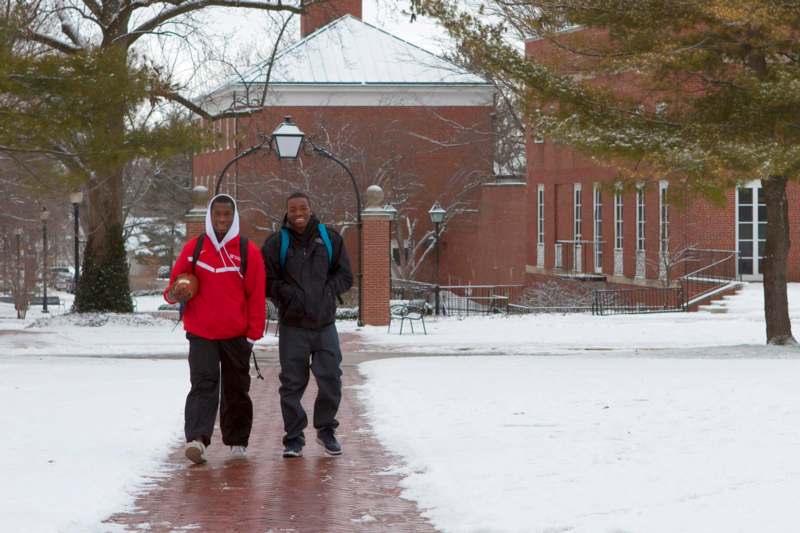 two men walking on a sidewalk in the snow