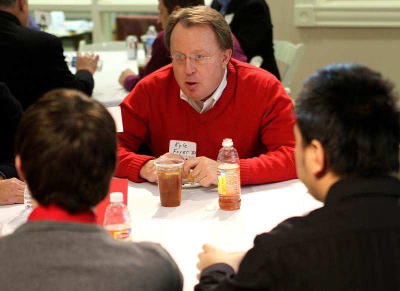 a man in a red sweater sitting at a table with drinks