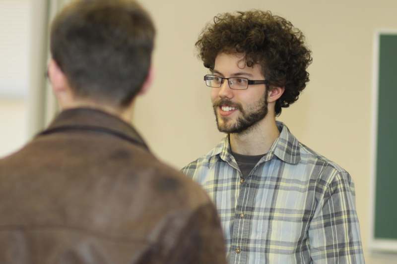 a man with curly hair and beard talking to another man