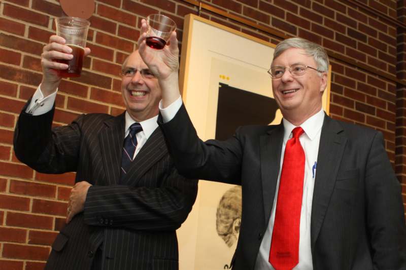men in suits holding up glasses of liquid