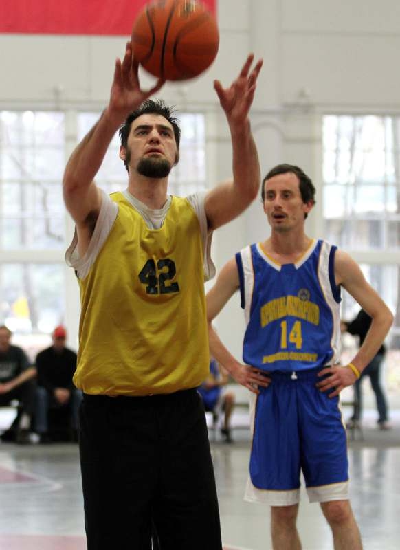 a man in a yellow shirt and blue shorts with a basketball in the air