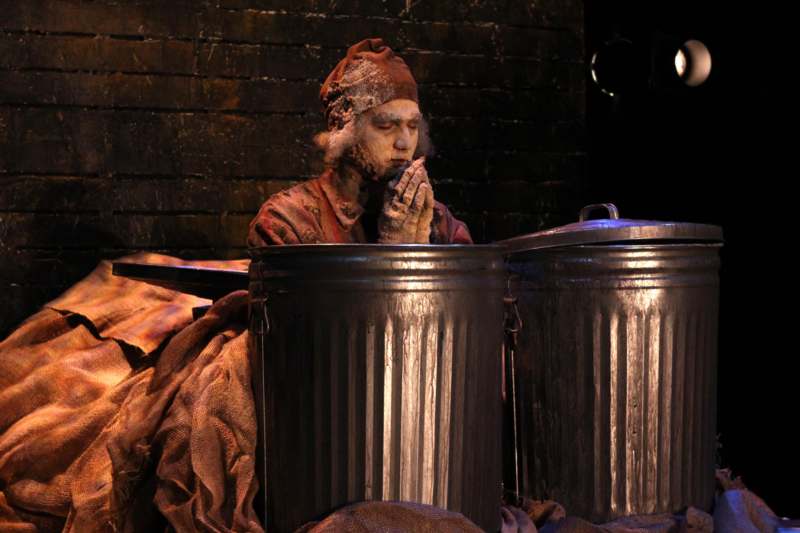 a man in a garment sitting in a trash can