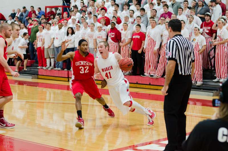 a basketball player running with a basketball in front of a crowd